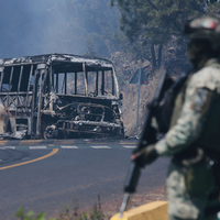 Ein Soldat steht in Mexiko - einem der drei Ausrichterländer der Fußball-WM im Sommer - neben einem ausgebrannten Bus. - Foto: Armando Solis/AP/dpa