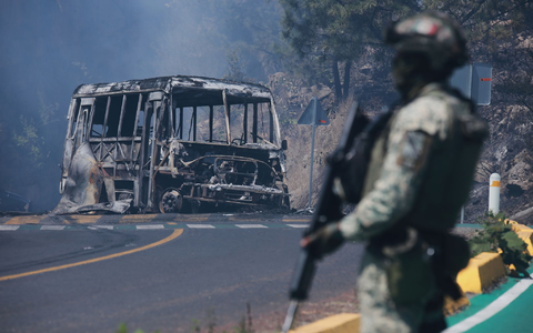 Ein Soldat steht in Mexiko - einem der drei Ausrichterländer der Fußball-WM im Sommer - neben einem ausgebrannten Bus. - Foto: Armando Solis/AP/dpa