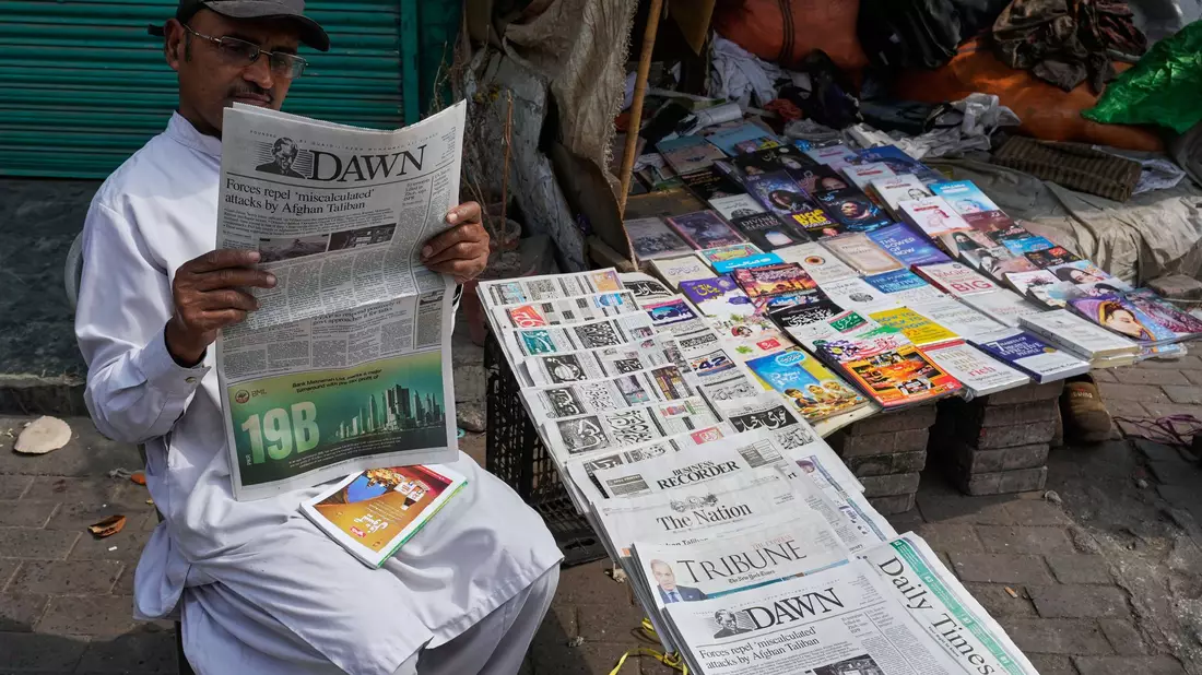Ein Pakistaner liest an einem Verkaufsstand eine Morgenzeitung, die über die nächtlichen grenzüberschreitenden Kämpfe zwischen pakistanischen und afghanischen Streitkräften berichtet. - Bild: K.M. Chaduary/AP/dpa