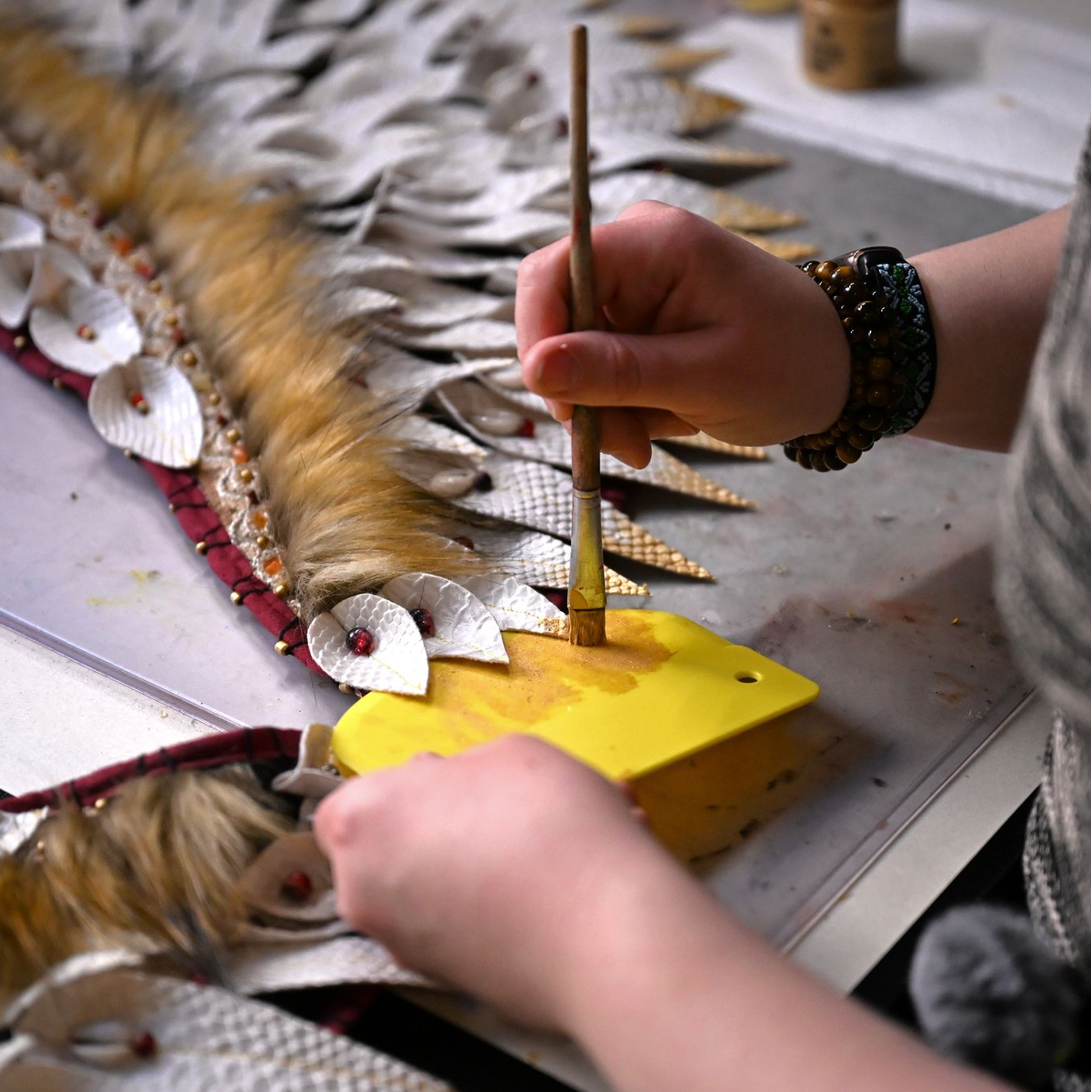 Mit Pinsel und goldener Farbe bemalt Toni ihr Kostüm.  - Foto: Jennifer Brückner/dpa