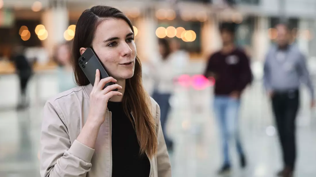 Die für KI zuständige Telekom-Mitarbeiterin Lena Drubel führt bei einer Testvorführung des KI-Assistenten ein Handytelefonat. - Bild: Oliver Berg/dpa