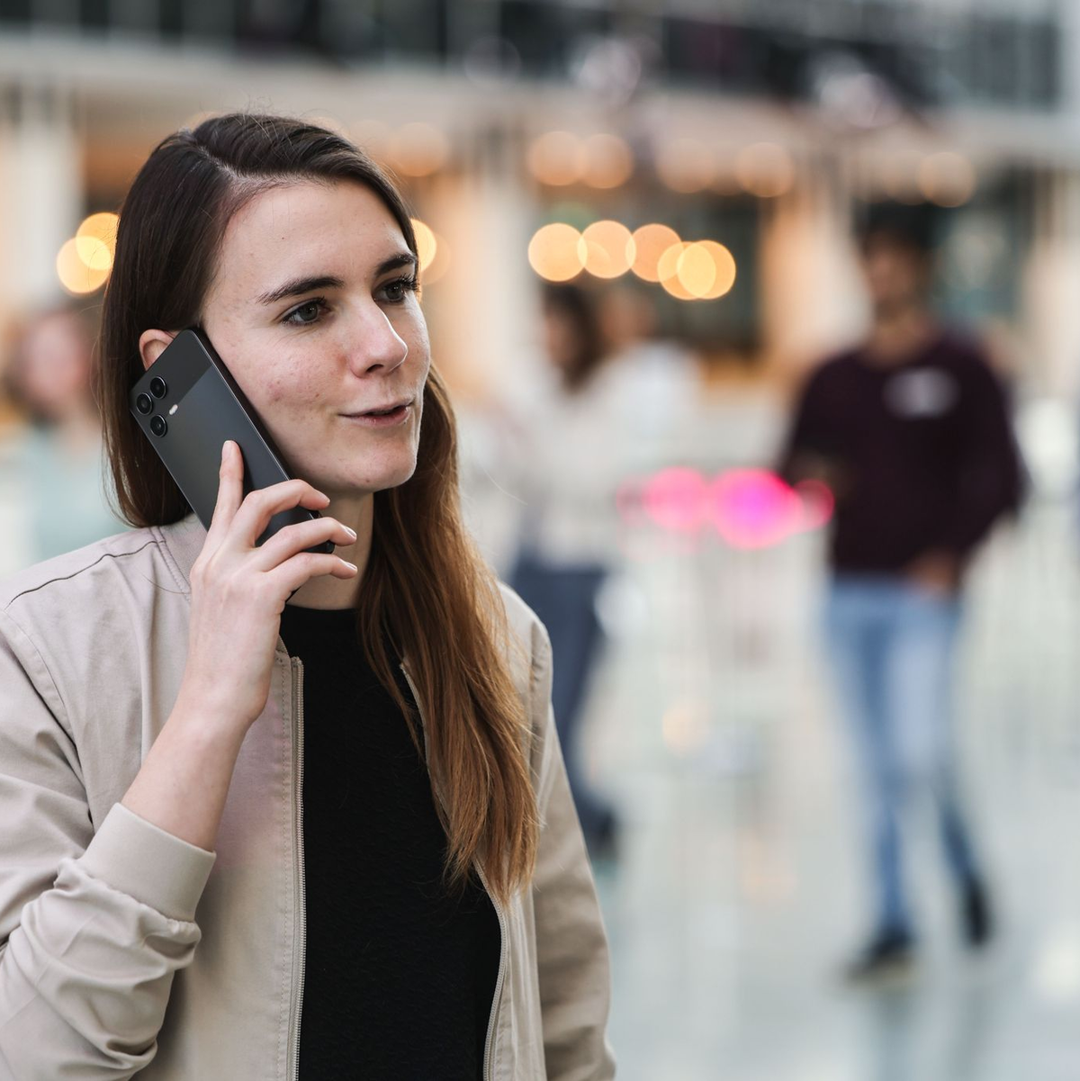 Die für KI zuständige Telekom-Mitarbeiterin Lena Drubel führt bei einer Testvorführung des KI-Assistenten ein Handytelefonat. - Foto: Oliver Berg/dpa