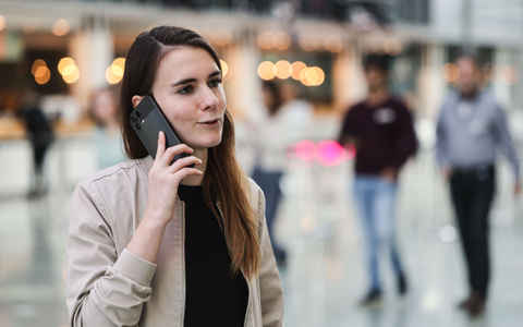 Die für KI zuständige Telekom-Mitarbeiterin Lena Drubel führt bei einer Testvorführung des KI-Assistenten ein Handytelefonat. - Foto: Oliver Berg/dpa