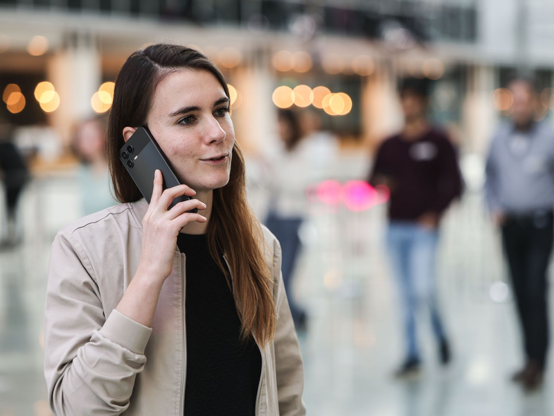 Die für KI zuständige Telekom-Mitarbeiterin Lena Drubel führt bei einer Testvorführung des KI-Assistenten ein Handytelefonat. - Foto: Oliver Berg/dpa
