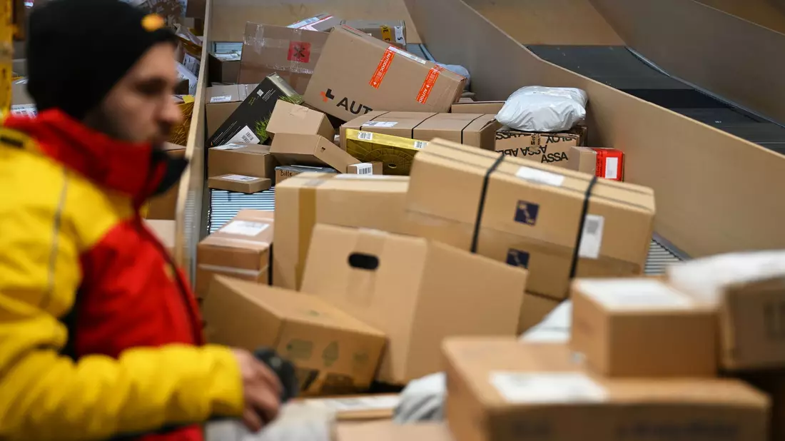 Ein DHL-Paketbote ist in einer Zustellbasis mit einer Vielzahl an Paketen beschäftigt. Der Logistikkonzern hat Jahreszahlen für 2025 vorgelegt, er hat profitablere Geschäfte gemacht als zuvor. - Bild: Wolf von Dewitz/dpa