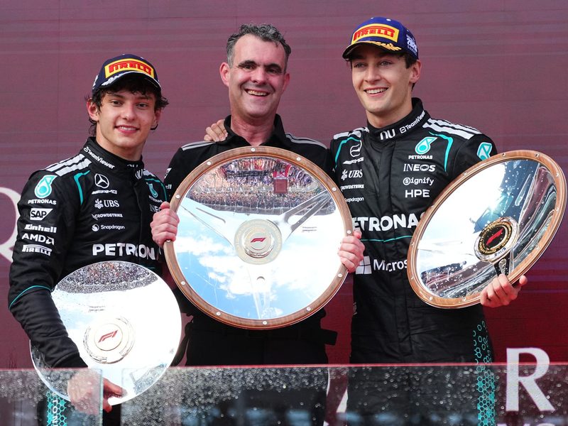 George Russell (r) freut sich über Silbergeschirr. - Foto: Scott Barbour/AP/dpa