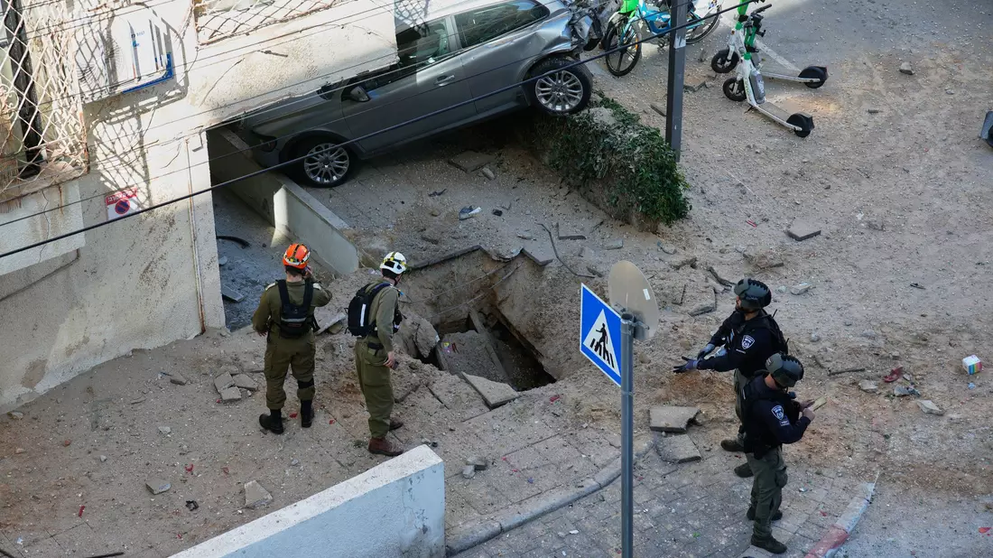 Nach einem Raketeneinschlag in Tel Aviv sind Anwohner schockiert. - Bild: Ohad Zwigenberg/AP/dpa
