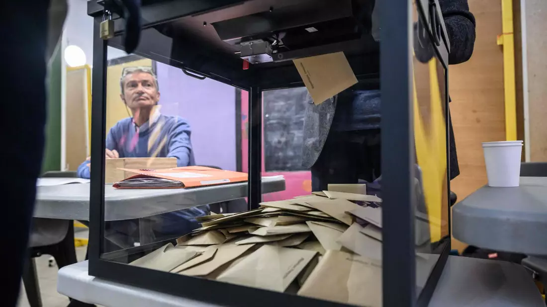 Ein Beamter beobachtet, wie Wähler während der ersten Runde der französischen Kommunalwahlen 2026 in Perpignan, Südfrankreich, ihre Stimme abgeben. - Bild: Ed Jones/AFP/dpa