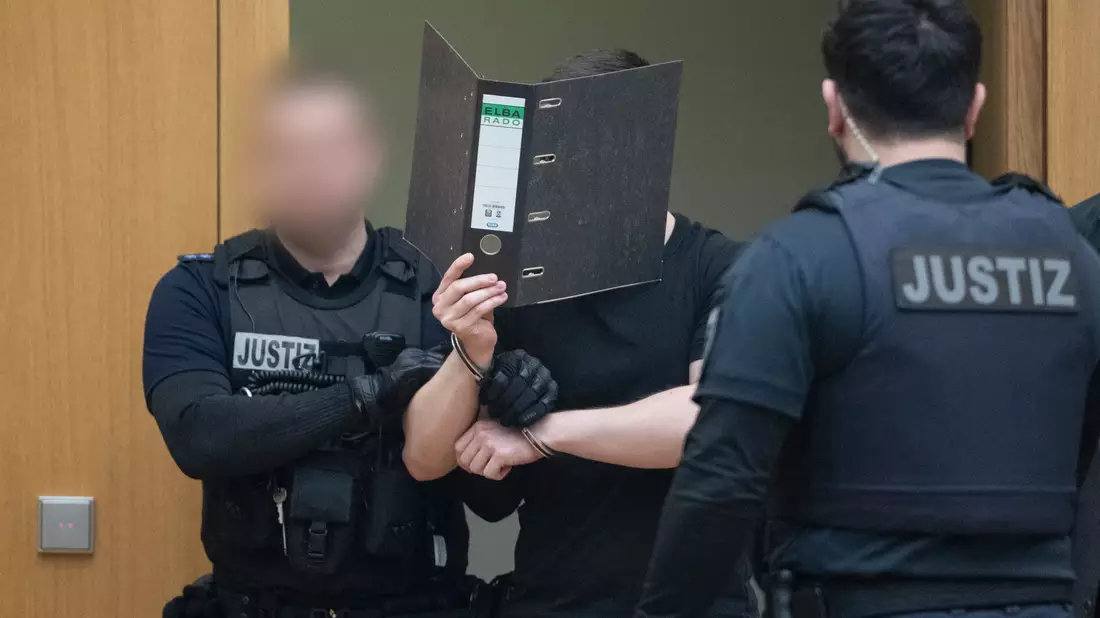 Zwei der Männer verdeckten beim Betreten des Gerichtssaals ihr Gesicht. - Bild: dpa
