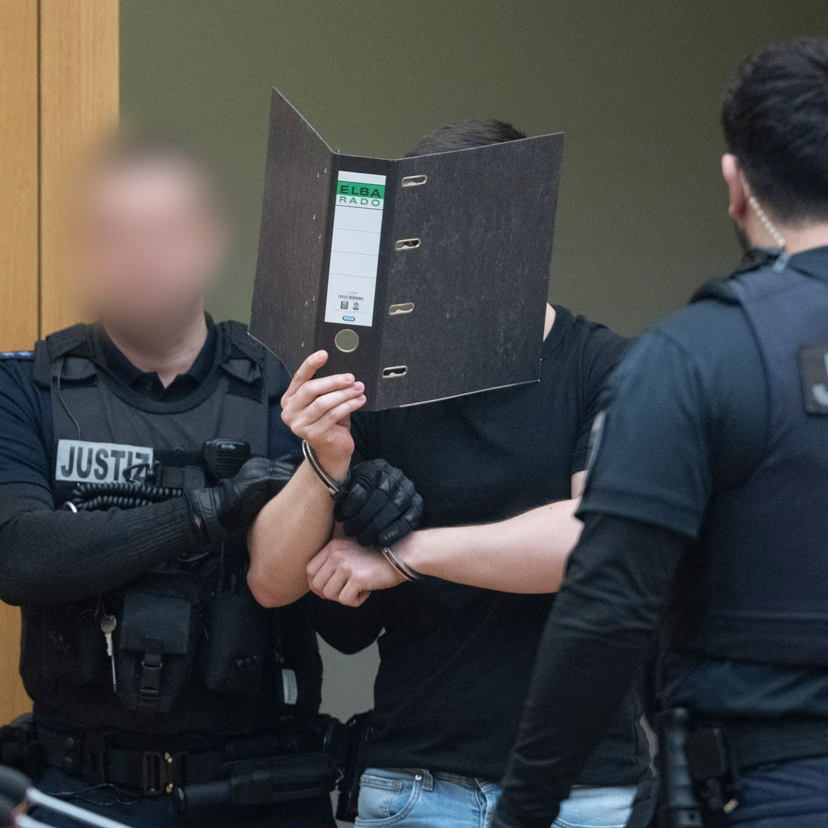 Zwei der Männer verdeckten beim Betreten des Gerichtssaals ihr Gesicht. - Foto: dpa