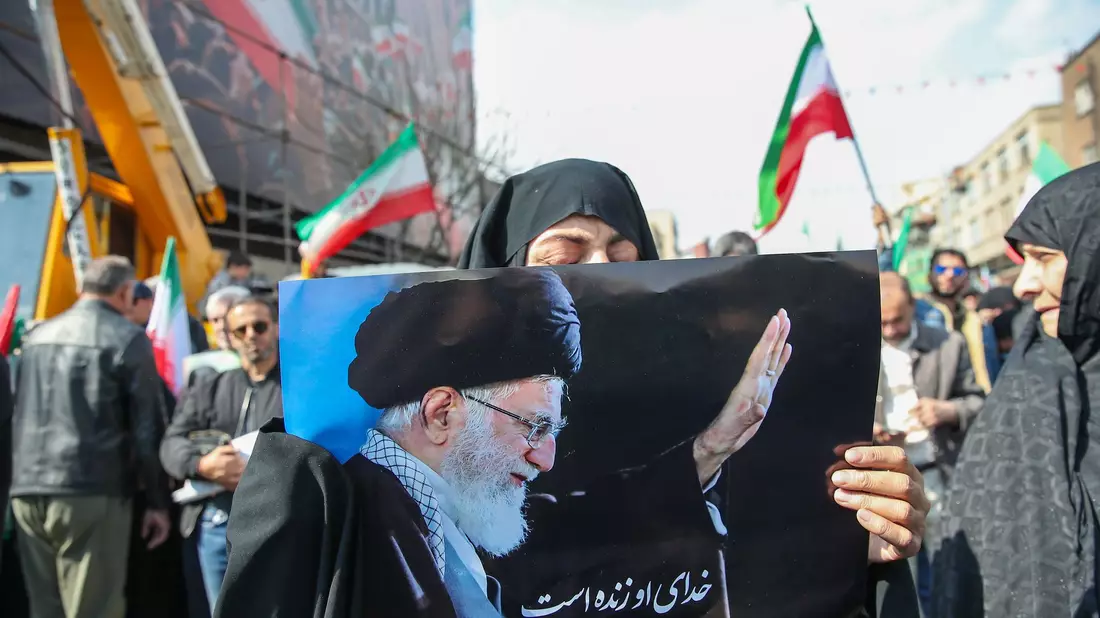 Eine Trauernde hält beim Begräbnis des von Israel getöteten Generalsekretärs des iranischen Sicherheitsrats, Ali Laridschani, ein Bild des ebenfalls getöteten Obersten Führers Ajatollah Ali Chamenei in die Höhe.  - Bild: Stringer/dpa