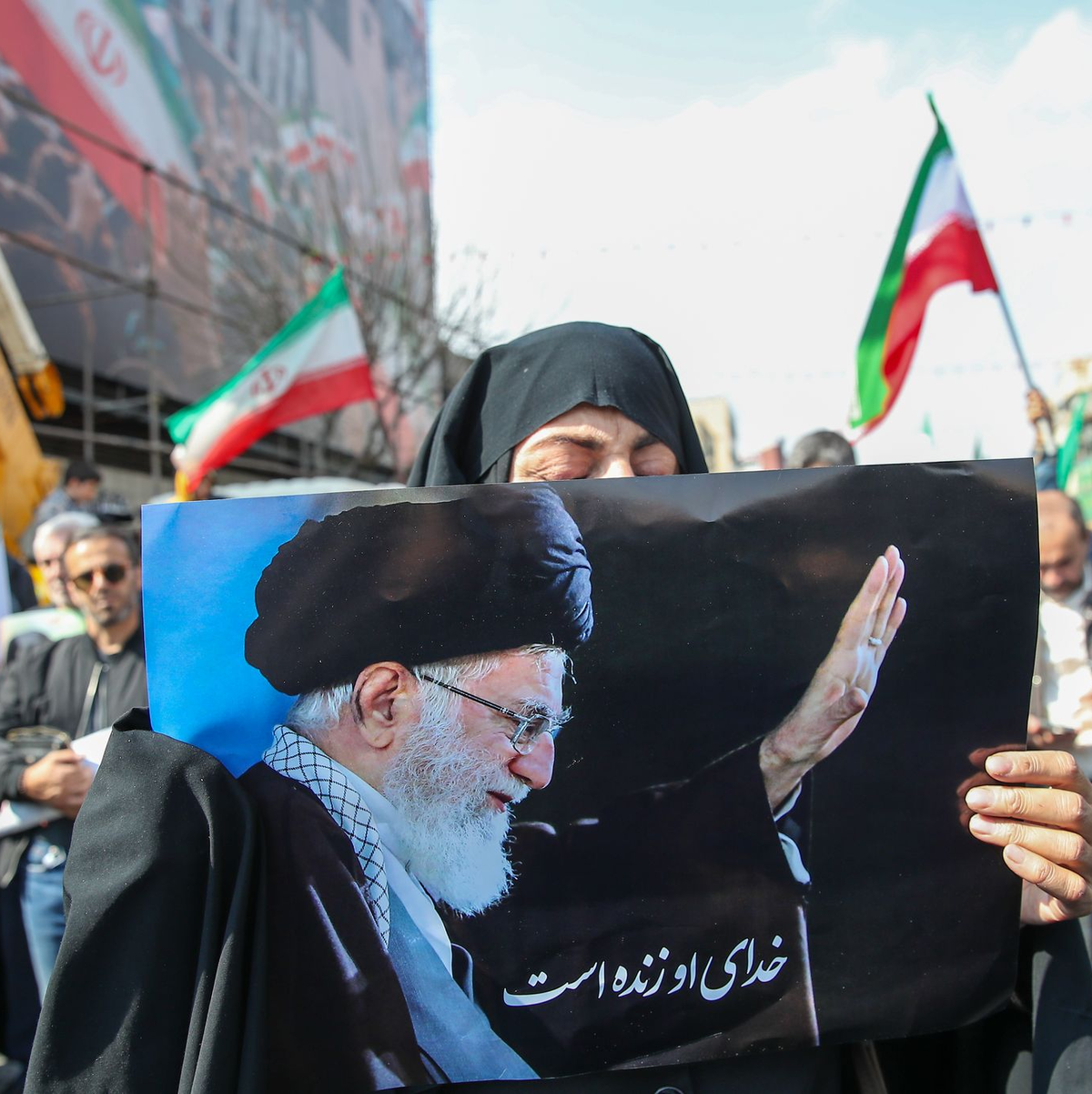 Eine Trauernde hält beim Begräbnis des von Israel getöteten Generalsekretärs des iranischen Sicherheitsrats, Ali Laridschani, ein Bild des ebenfalls getöteten Obersten Führers Ajatollah Ali Chamenei in die Höhe.  - Foto: Stringer/dpa