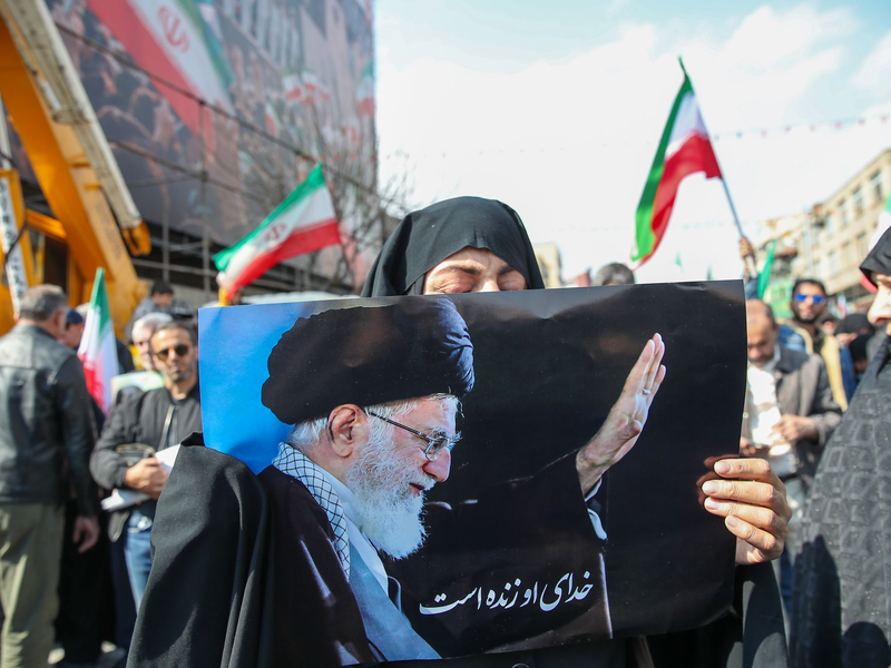 Eine Trauernde hält beim Begräbnis des von Israel getöteten Generalsekretärs des iranischen Sicherheitsrats, Ali Laridschani, ein Bild des ebenfalls getöteten Obersten Führers Ajatollah Ali Chamenei in die Höhe.  - Foto: Stringer/dpa