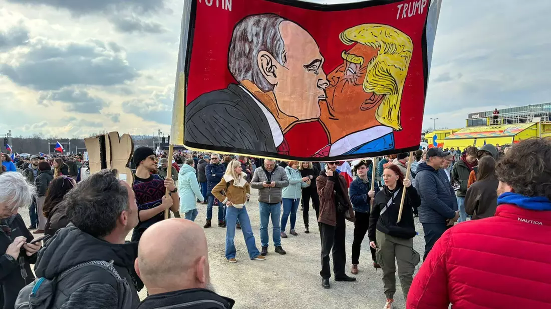 Demonstranten halten bei einer Kundgebung des Bündnisses «Eine Million Augenblicke für Demokratie» ein Banner, auf dem sich stilisiert US-Präsident Trump und Russlands Präsident Putin küssen. - Bild: Michael Heitmann/dpa