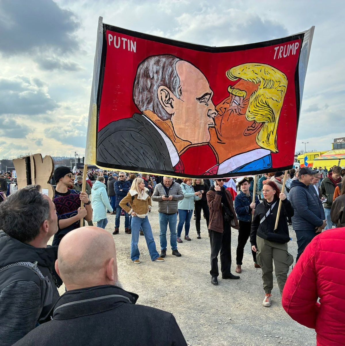 Demonstranten halten bei einer Kundgebung des Bündnisses «Eine Million Augenblicke für Demokratie» ein Banner, auf dem sich stilisiert US-Präsident Trump und Russlands Präsident Putin küssen. - Foto: Michael Heitmann/dpa