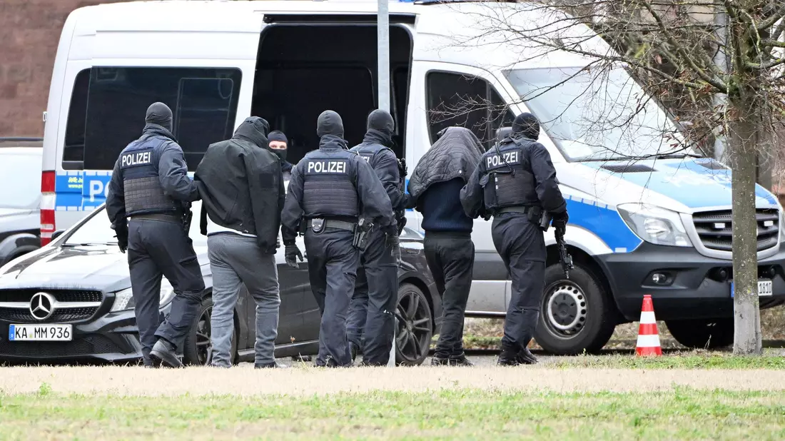 Zwei mutmaßliche Hamas-Mitglieder werden von Polizisten bei einem Hubschrauberlandeplatz von einem Hubschrauber zu einem Auto geführt. (Archivbild) - Bild: Uli Deck/dpa