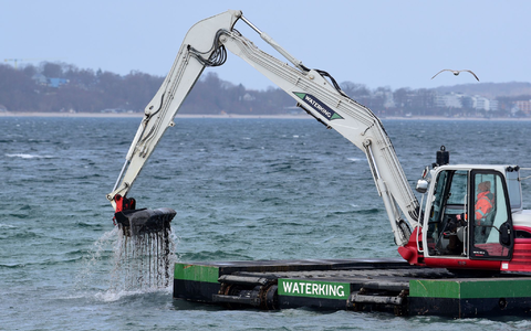 Der Bagger gräbt eine Rinne für den gestrandeten Wal. - Foto: Daniel Bockwoldt/dpa
