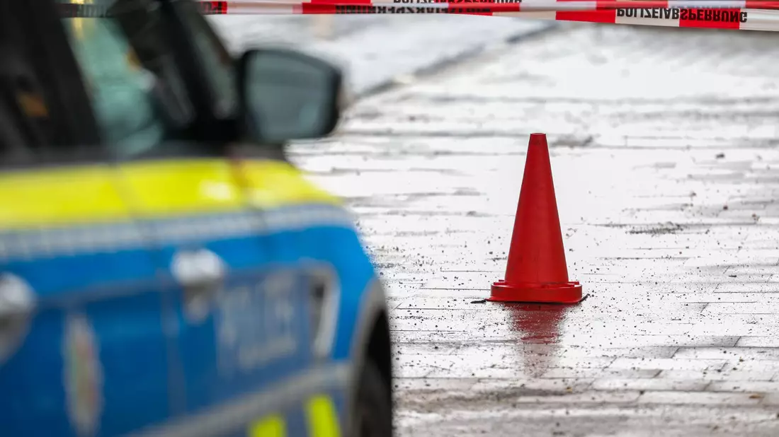 Polizeibeamte bewachen in einem Streifenwagen den Tatort. - Bild: Christoph Reichwein/dpa