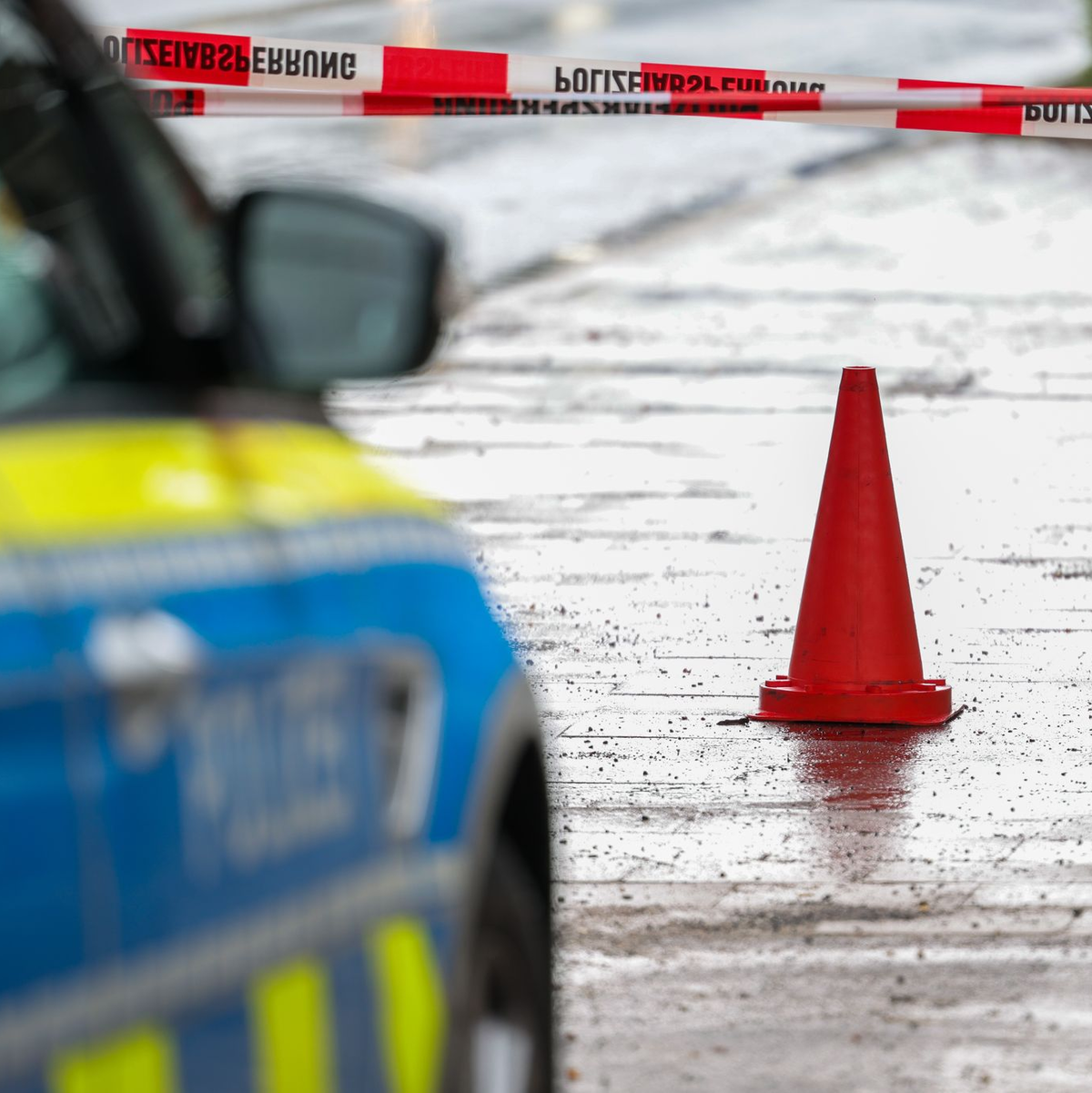 Polizeibeamte bewachen in einem Streifenwagen den Tatort. - Foto: Christoph Reichwein/dpa