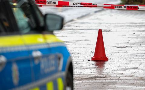 Polizeibeamte bewachen in einem Streifenwagen den Tatort. - Foto: Christoph Reichwein/dpa