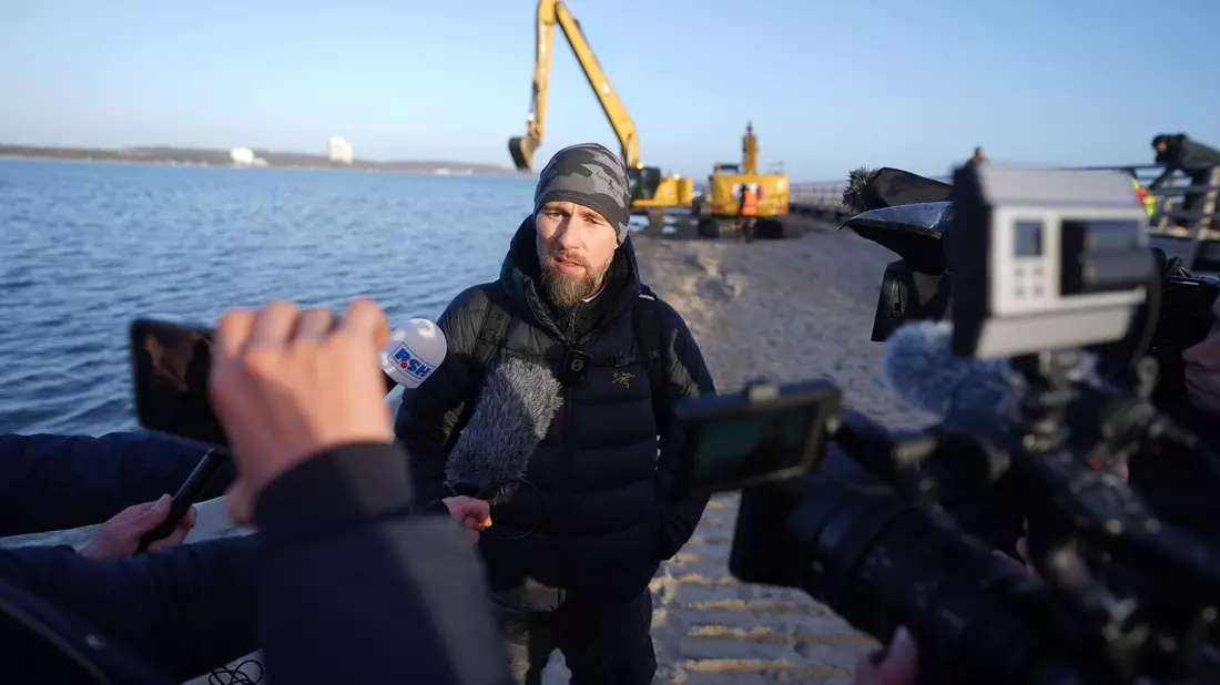 Robert Marc Lehmann spricht mit den Medien am Strand, in dessen Nähe der gestrandete Buckelwal im Wasser gelegen hatte. - Bild: Marcus Brandt/dpa