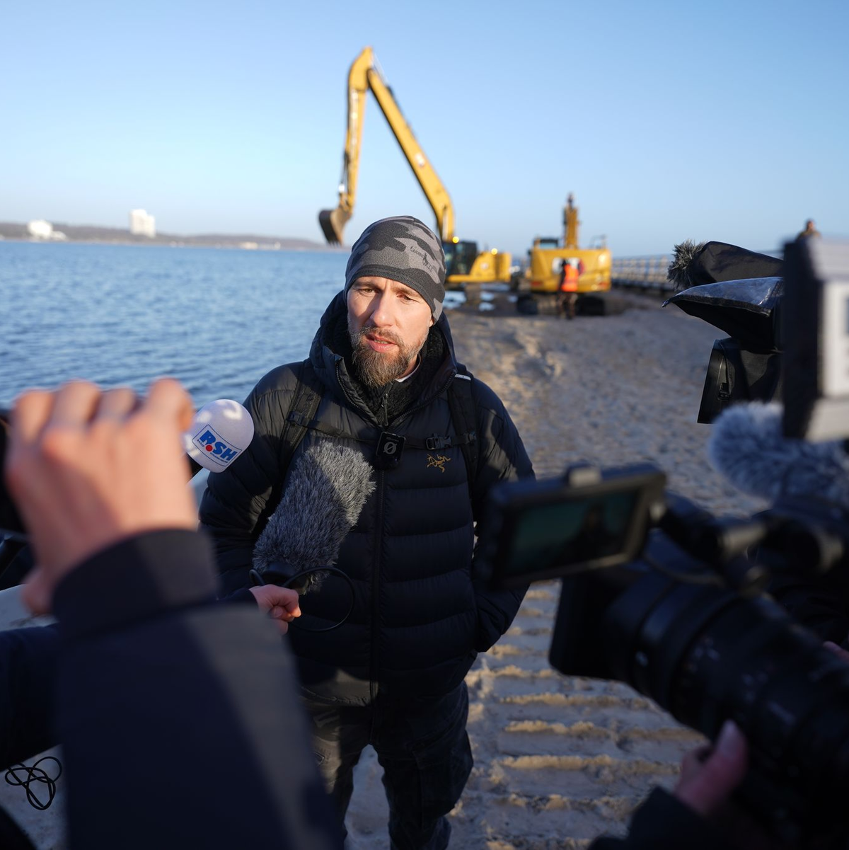 Robert Marc Lehmann spricht mit den Medien am Strand, in dessen Nähe der gestrandete Buckelwal im Wasser gelegen hatte. - Foto: Marcus Brandt/dpa