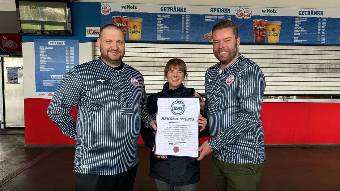 Das Catering-Team des Ostseestadions Rostock um Geschäftsführer Christoph Wulff (r) und Küchenchef Jens Schaumburg (l) hat das längste Fischbrötchen der Welt produziert. Bestätigt wurde der Rekord von Laura Koblischek (M) vom Rekord-Institut Deutschland. (Foto Handout) - Bild: --/F.C. Hansa Rostock /dpa