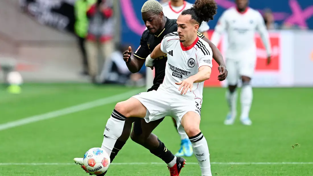 Der 1. FC Köln um Ragnar Ache (l) hatte gegen Eintracht Frankfurt um Arthur Theate früh im Spiel eine Topchance. - Bild: Uwe Anspach/dpa