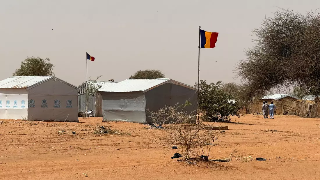 Die tschadische Fahne weht am Eingang des Flüchtlingslagers Aboutengé. - Bild: Eva Krafczyk/dpa