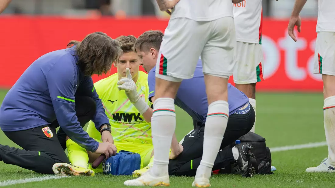 Auch eine kurze Behandlungspause nach einer Abwehr mit dem Kopf konnte Augsburgs Keeper Finn Dahmen nicht aus dem Rhythmus bringen.  - Bild: Rolf Vennenbernd/dpa