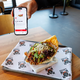 Zwei Mal Krispy Kebab: einmal auf dem Smartphone in der KFC-App und einmal auf einem Tablett in einer Krispy-Kebab-Filiale. - Foto: Friso Gentsch/dpa