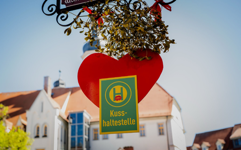 Rotes Herz und Mistelzweig: Auf dem Marktplatz in Eisenberg ist Küssen ausdrücklich erwünscht. - Foto: Jacob Schröter/dpa