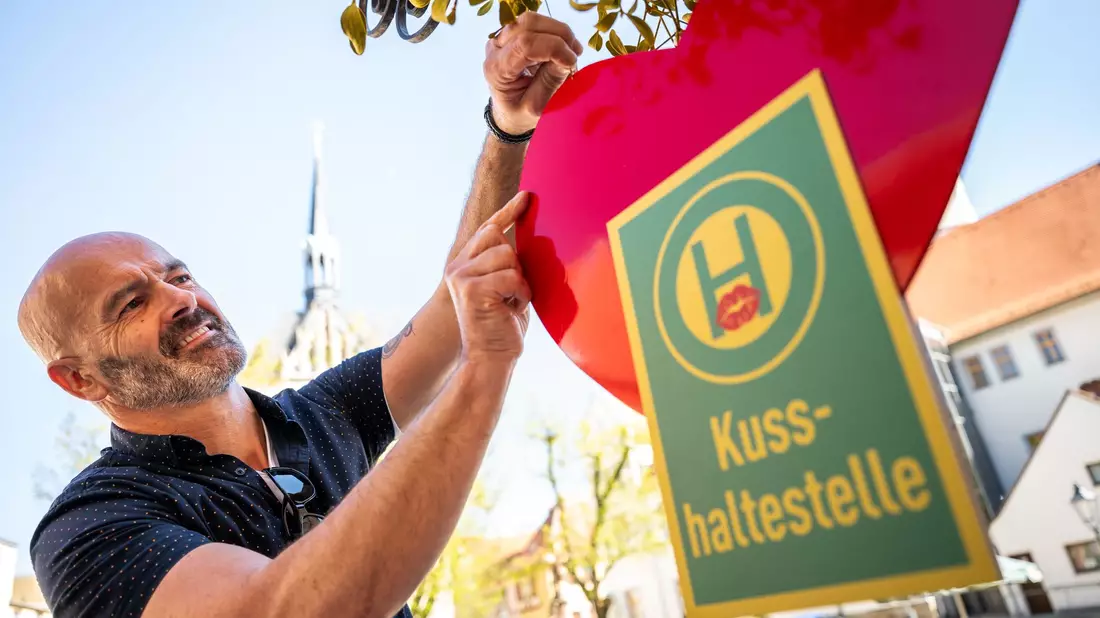 Café-Betreiber Jost Samorski will mit seiner «Kusshaltestelle» in Eisenberg Passanten zum Küssen animieren.  - Bild: Jacob Schröter/dpa