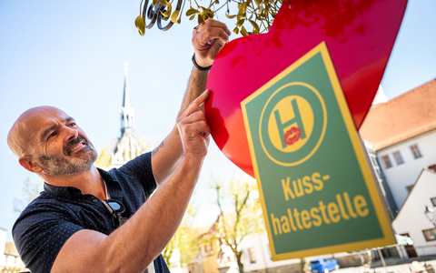 Café-Betreiber Jost Samorski will mit seiner «Kusshaltestelle» in Eisenberg Passanten zum Küssen animieren.  - Foto: Jacob Schröter/dpa