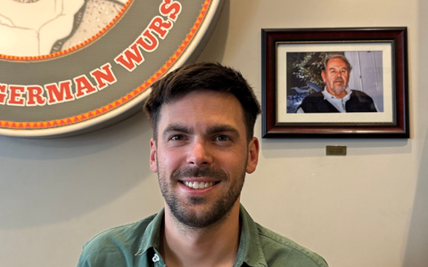 Fabian Förster steht vor einem Foto seines Großvaters, nach dem «Dieters Grill» benannt wurde. - Foto: Eva Krafczyk/dpa