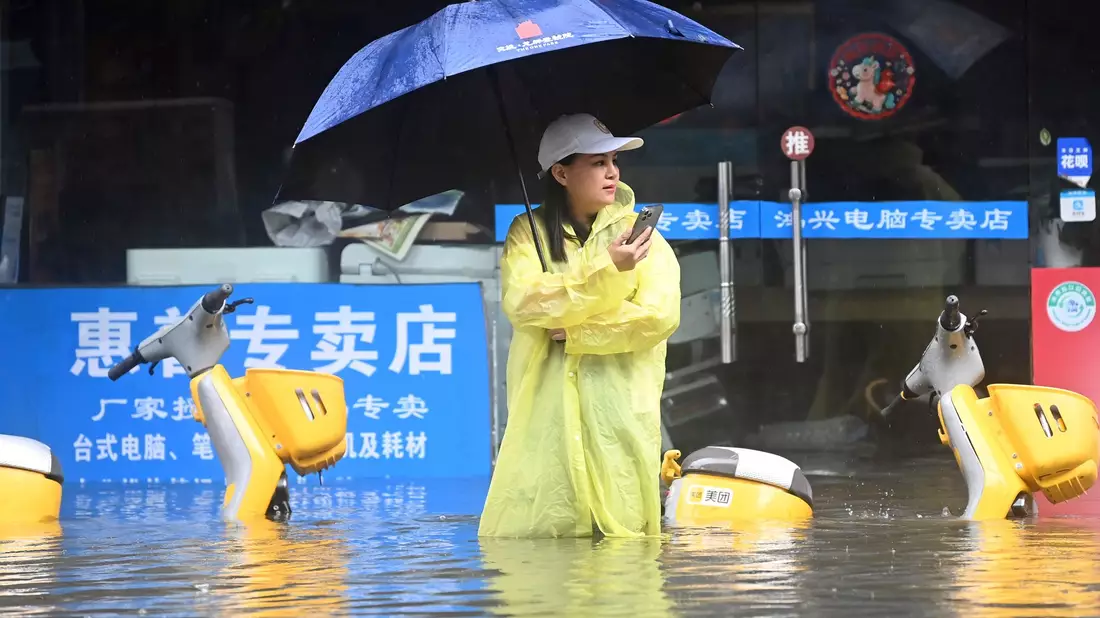 Eine Frau steht in Qinzhou auf einer mit Wasser vollgelaufenen Straße. - Bild: Zhang Ailin/XinHua/dpa