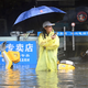 Eine Frau steht in Qinzhou auf einer mit Wasser vollgelaufenen Straße. - Foto: Zhang Ailin/XinHua/dpa