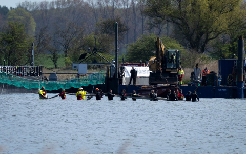 Helfer versuchen den gestrandeten Wal aus dem flachen Wasser zu einem Transportschiff zu ziehen, das in der Fahrrinne wartet. - Foto: Philip Dulian/dpa