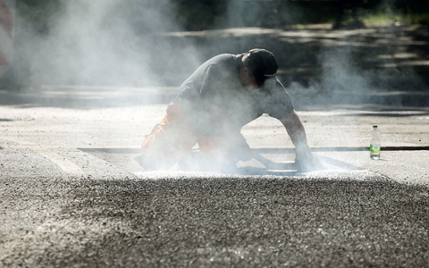 Ein Bauarbeiter repariert eine Straße in Berlin mit Bitumen, einem Bindemittel für Asphalt. (Symbolbild) - Foto: Wolfgang Kumm/dpa