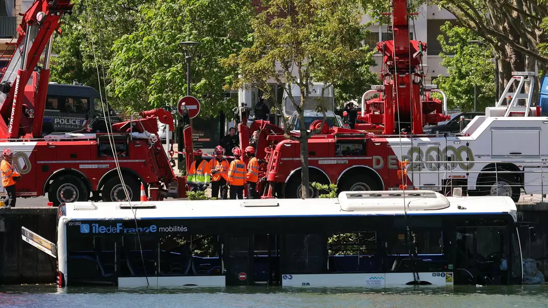 Der Linienbus wird von Kränen aus dem Fluss geborgen. - Bild: Thomas Samson/AFP/dpa