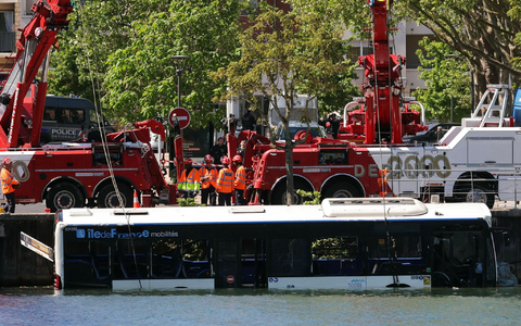 Der Linienbus wird von Kränen aus dem Fluss geborgen. - Foto: Thomas Samson/AFP/dpa