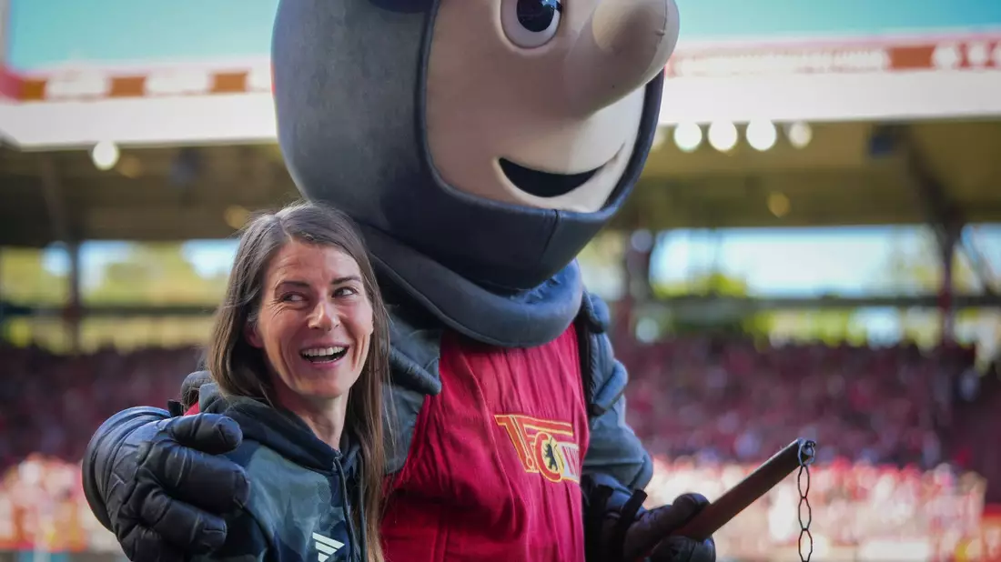 Union-Trainerin Marie-Louise Eta wird von Club-Maskottchen Ritter Keule umarmt.  - Bild: Soeren Stache/dpa