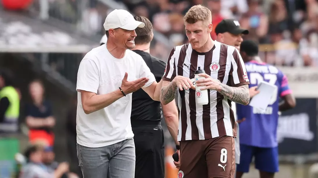 St. Paulis Trainer Alexander Blessin (l) spricht mit Eric Smith. - Bild: Christian Charisius/dpa