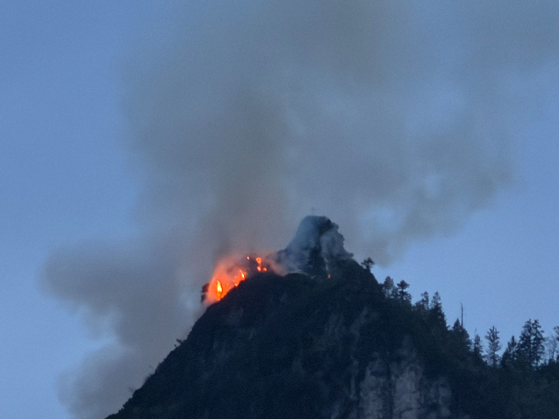 Noch immer steigen große Rauchwolken aus einem bewaldeten Berg bei Ruhpolding (Landkreis Traunstein) auf. - Foto: Matthias Brüning/dpa