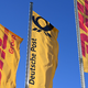 Eine Deutsche-Post-Fahne an der Konzernzentrale, umrahmt von DHL-Fahnen. - Foto: Wolf von Dewitz/dpa