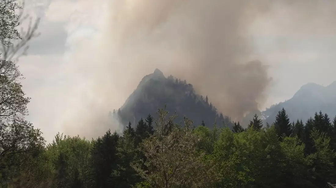 Dichter Rauch ist über dem Berg in den bayerischen Alpen zu sehen. - Bild: Gabriel Neumayr/dpa