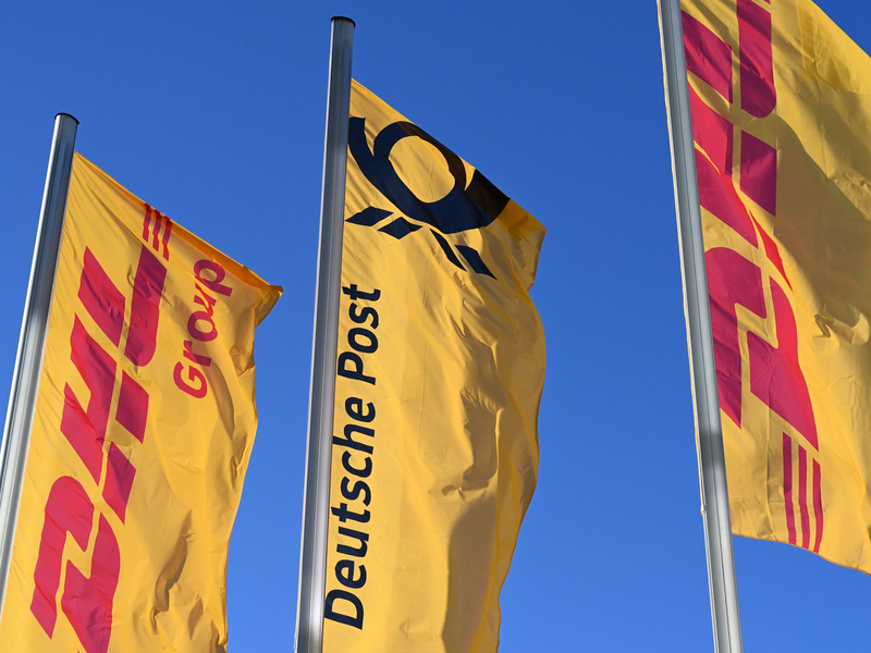 Eine Deutsche-Post-Fahne an der Konzernzentrale, umrahmt von DHL-Fahnen. - Foto: Wolf von Dewitz/dpa