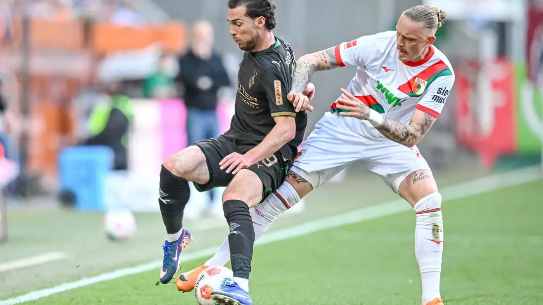 Augsburg Marius Wolf (r) nimmt dem Gladbacher Joe Scally den Ball ab. - Bild: Harry Langer/dpa