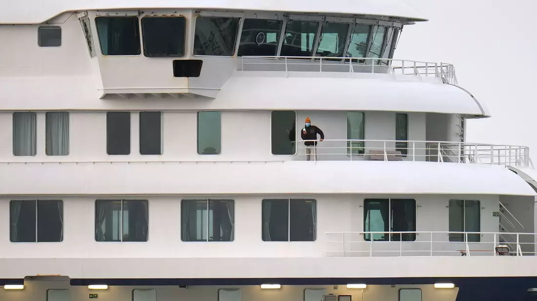 Eine Person mit Maske steht an Bord des Kreuzfahrtschiffes «Hondius» nach der Ankunft im Hafen von Granadilla. - Bild: Manu Fernandez/AP/dpa
