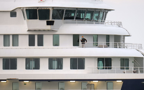 Eine Person mit Maske steht an Bord des Kreuzfahrtschiffes «Hondius» nach der Ankunft im Hafen von Granadilla. - Foto: Manu Fernandez/AP/dpa